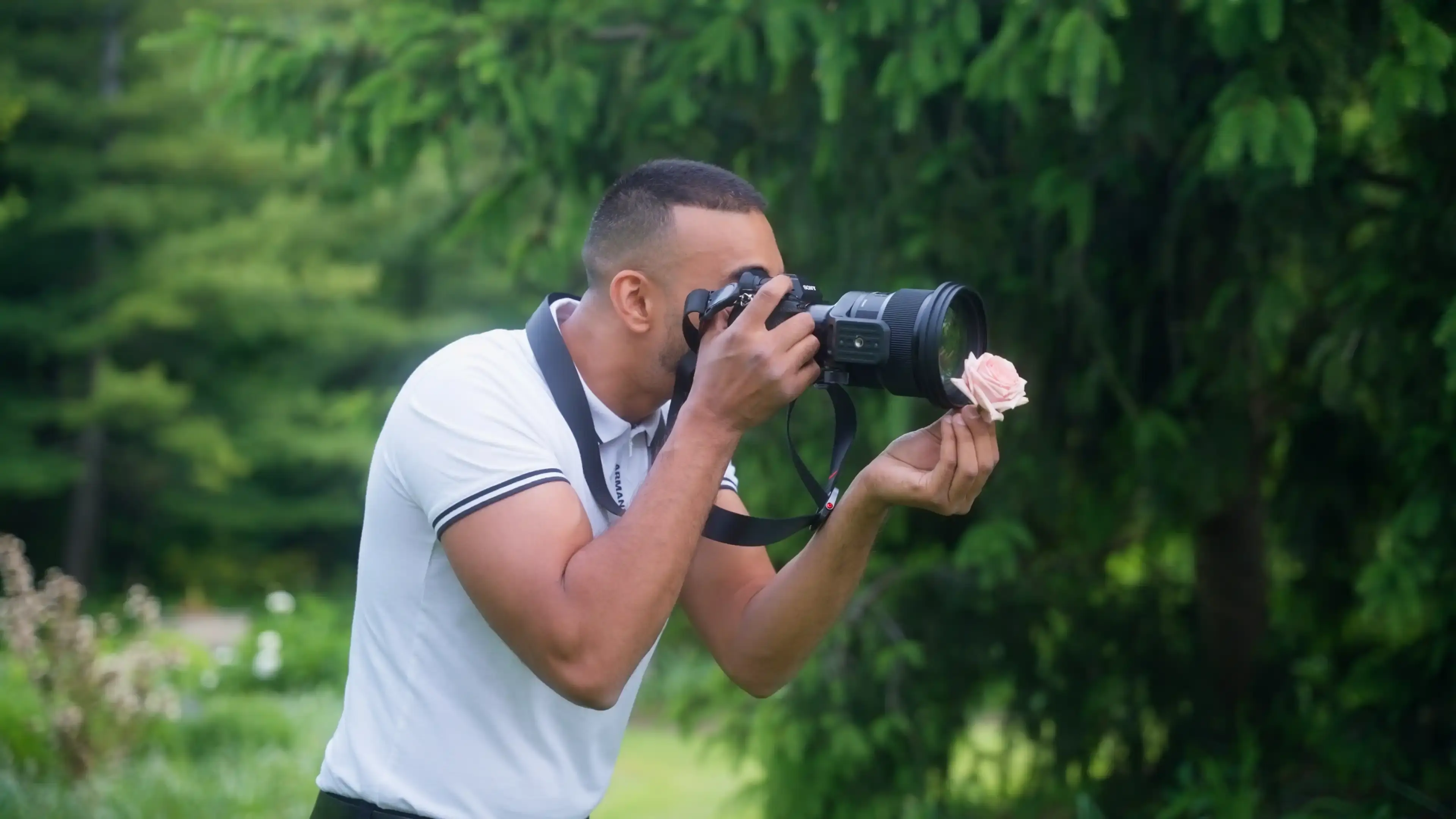Man holding a camera in front of a flower